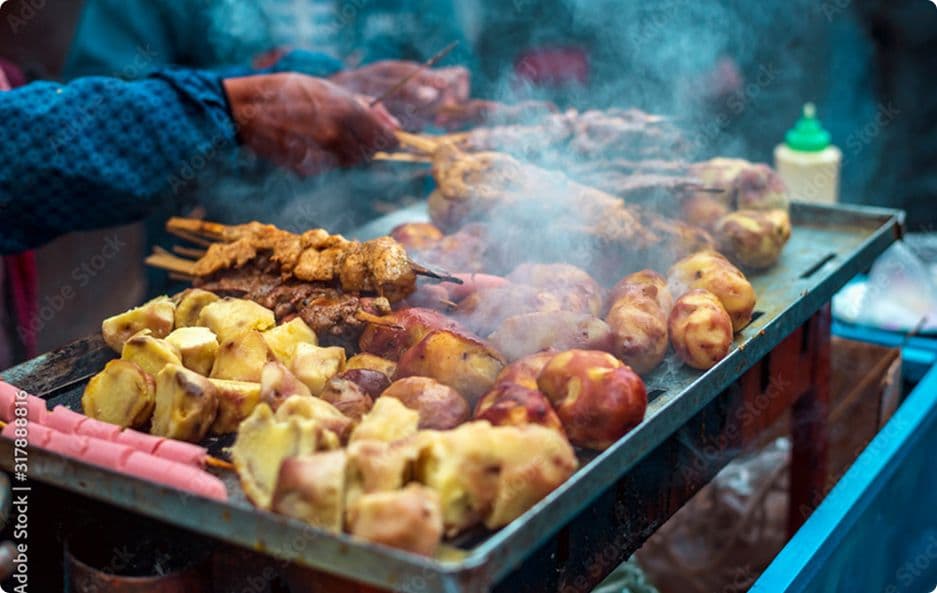 Anticuchos and potatoes sizzling on a street grill