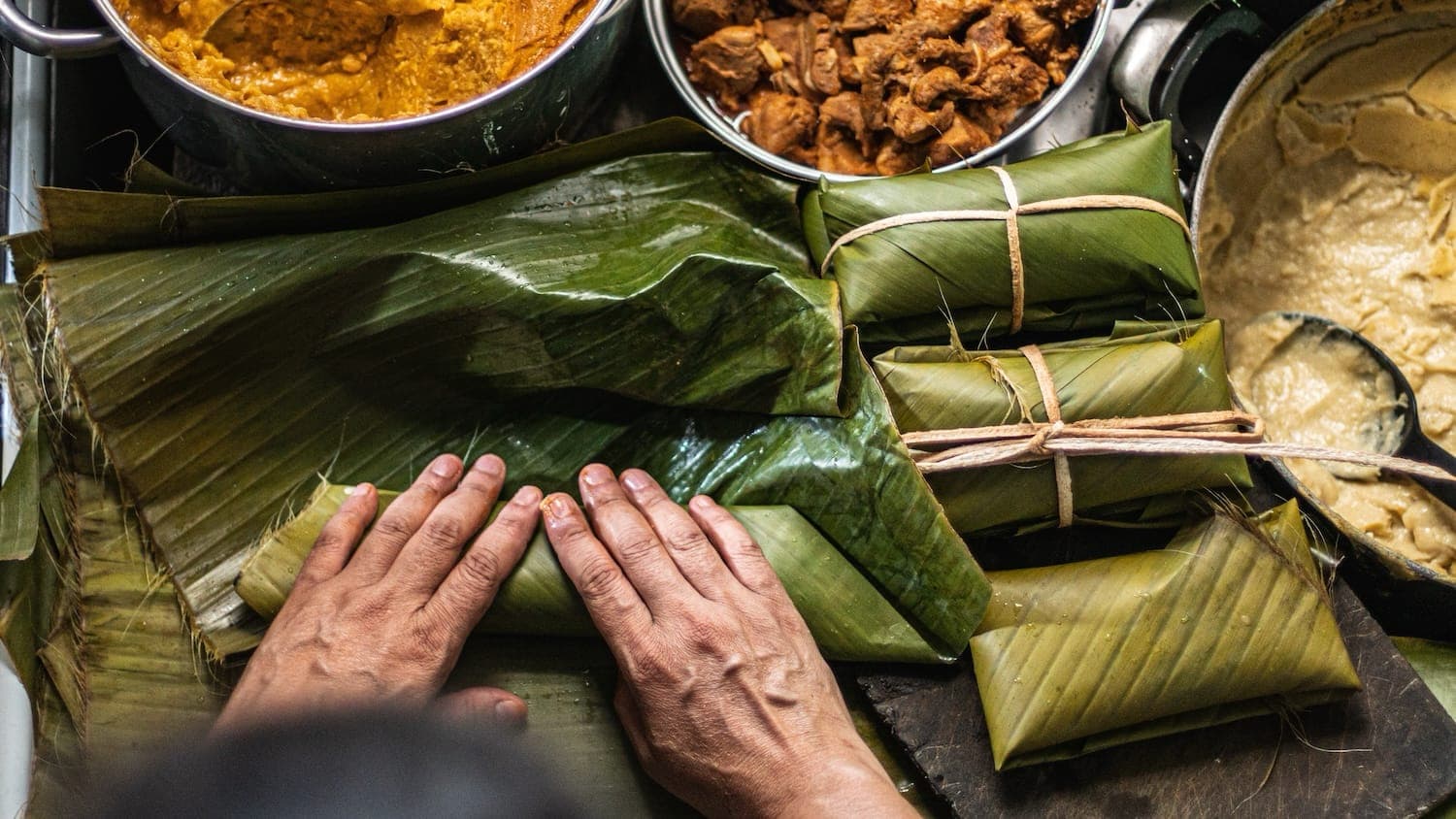 Food wrapped in banana leaves grilling over open coals